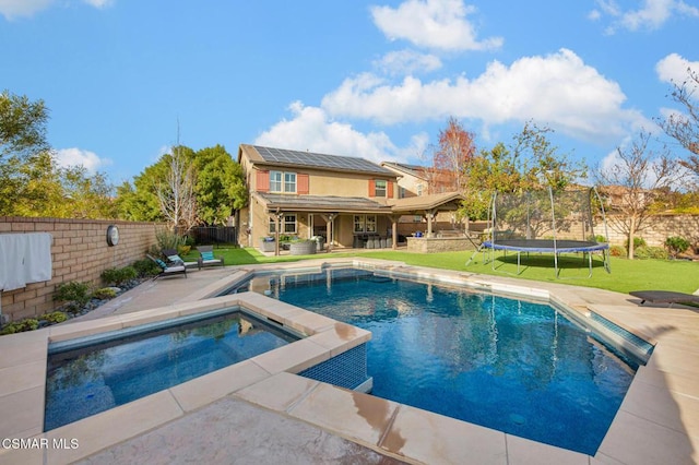 view of swimming pool with an in ground hot tub, a patio, a lawn, and a trampoline