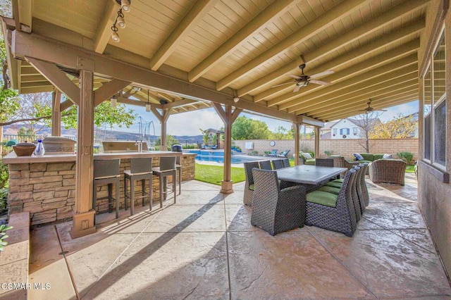 view of patio / terrace with ceiling fan, a fenced in pool, and a bar