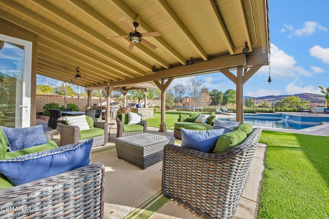 view of patio / terrace with ceiling fan, an outdoor hangout area, a mountain view, and a fenced in pool