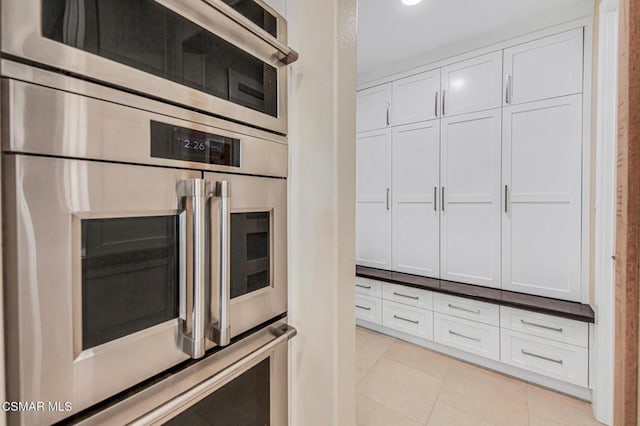 kitchen featuring light tile patterned floors, wall oven, and white cabinets