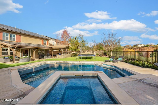 view of pool featuring an in ground hot tub, a patio area, an outdoor hangout area, and a trampoline