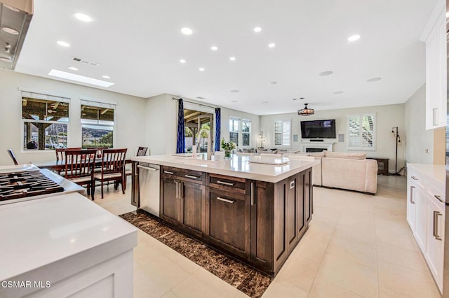 kitchen featuring sink, a kitchen island with sink, appliances with stainless steel finishes, plenty of natural light, and dark brown cabinets