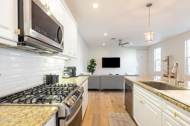 kitchen with white cabinets, hanging light fixtures, appliances with stainless steel finishes, and sink