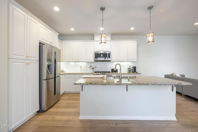 kitchen with light stone countertops, stainless steel appliances, white cabinets, and sink