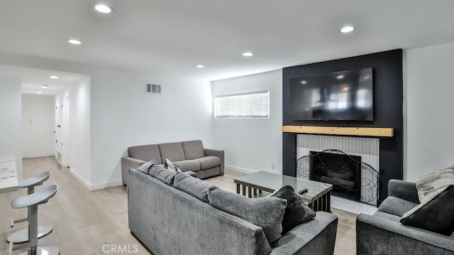 living room featuring light wood-type flooring and a tiled fireplace