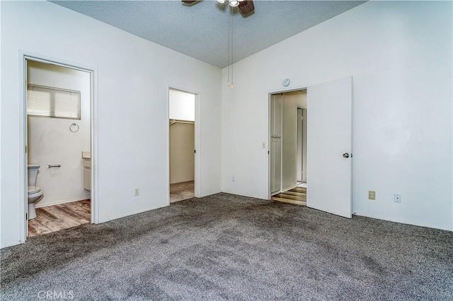 unfurnished bedroom with a spacious closet, connected bathroom, a closet, carpet flooring, and ceiling fan