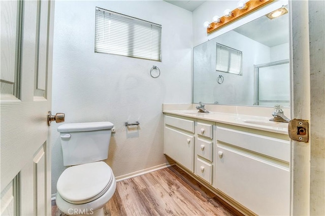 bathroom featuring toilet, vanity, wood-type flooring, and a shower with door