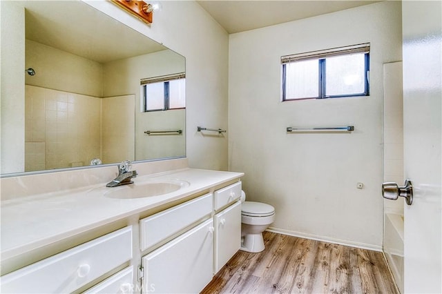 full bathroom featuring hardwood / wood-style flooring, a wealth of natural light, toilet, and vanity