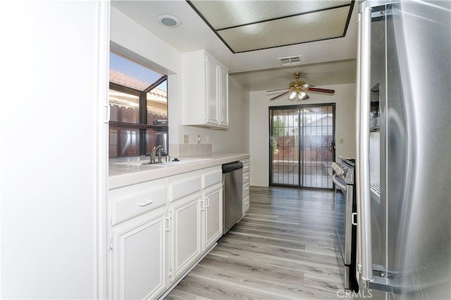 kitchen with ceiling fan, appliances with stainless steel finishes, white cabinets, light hardwood / wood-style flooring, and sink