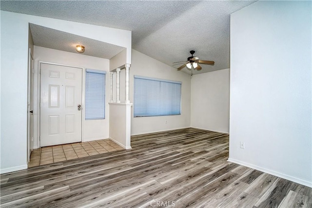 entrance foyer featuring ceiling fan, a textured ceiling, dark hardwood / wood-style flooring, and vaulted ceiling