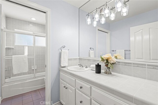 bathroom with tile patterned floors, vanity, and shower / bath combination with glass door