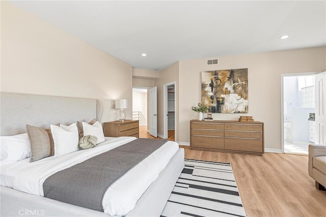 bedroom with light hardwood / wood-style floors, connected bathroom, a closet, and a walk in closet