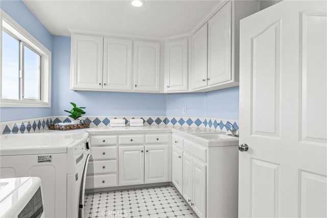 clothes washing area with cabinets, independent washer and dryer, and sink