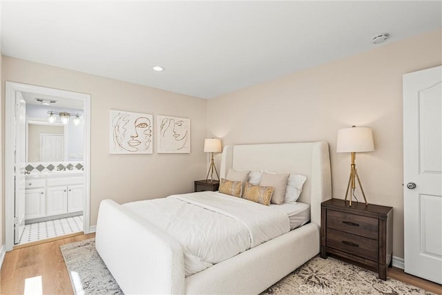 bedroom featuring ensuite bathroom and light wood-type flooring