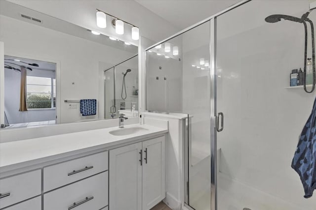 bathroom featuring a shower with shower door and vanity