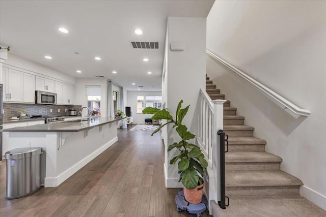 kitchen with dark wood-type flooring, white cabinetry, a breakfast bar area, decorative backsplash, and stove