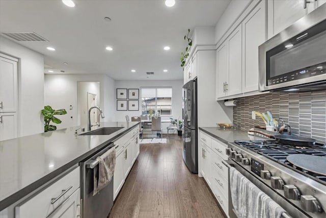 kitchen featuring white cabinets, stainless steel appliances, tasteful backsplash, sink, and dark hardwood / wood-style floors