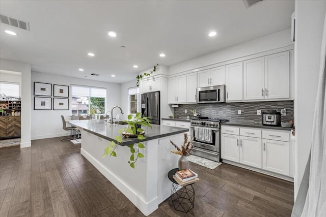 kitchen featuring dark wood-type flooring, stainless steel appliances, white cabinetry, and a breakfast bar