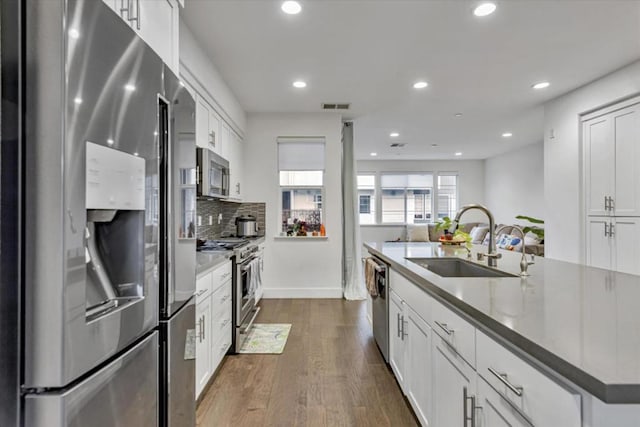 kitchen with white cabinets, premium appliances, sink, and dark hardwood / wood-style floors