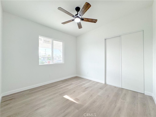 unfurnished bedroom with light wood-type flooring, ceiling fan, and a closet