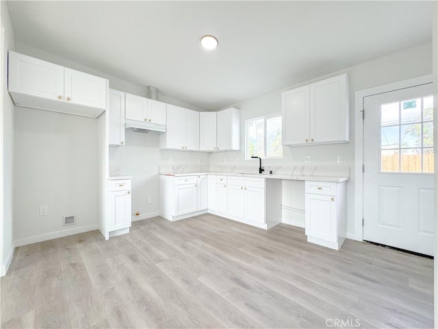 kitchen featuring white cabinets, light wood-type flooring, and sink