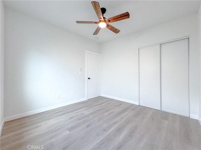 unfurnished bedroom featuring ceiling fan, light hardwood / wood-style floors, and a closet