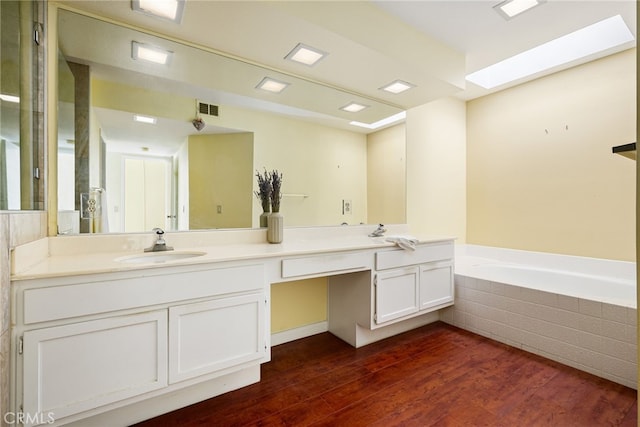 bathroom featuring vanity, hardwood / wood-style flooring, and a relaxing tiled tub