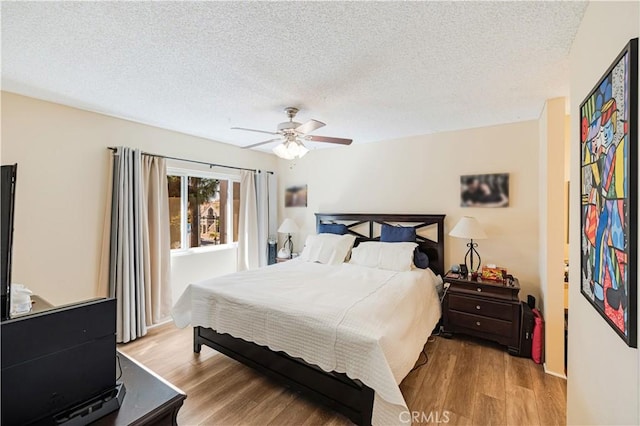 bedroom with ceiling fan, a textured ceiling, and light hardwood / wood-style flooring