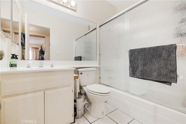 full bathroom featuring toilet, bath / shower combo with glass door, tile patterned floors, and vanity