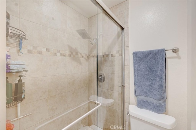 bathroom with a shower with shower door and toilet