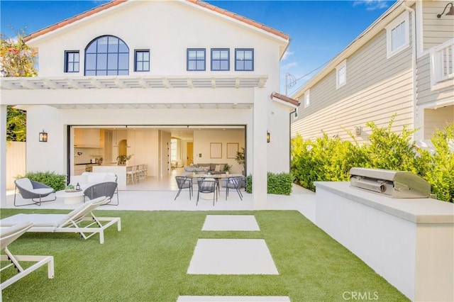 rear view of property featuring a lawn, exterior kitchen, a pergola, and a patio