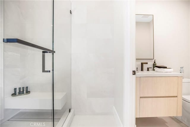 bathroom with toilet, a shower with shower door, and vanity