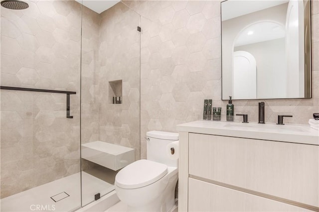 bathroom with toilet, vanity, tile walls, backsplash, and a tile shower