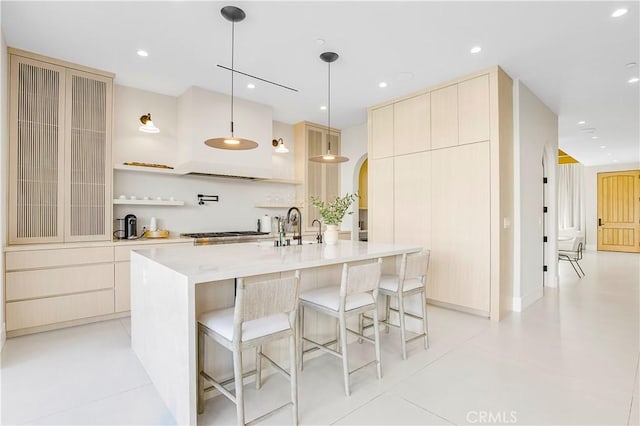 kitchen featuring a kitchen bar, an island with sink, light tile patterned flooring, hanging light fixtures, and sink