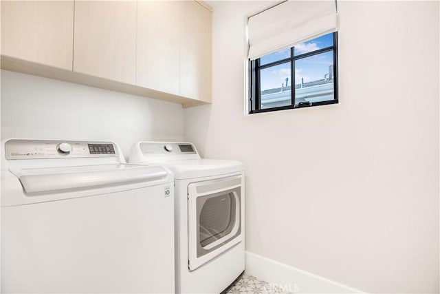 clothes washing area with washer and dryer and cabinets