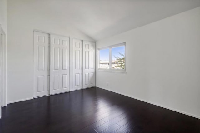 unfurnished bedroom featuring two closets, dark hardwood / wood-style floors, and lofted ceiling