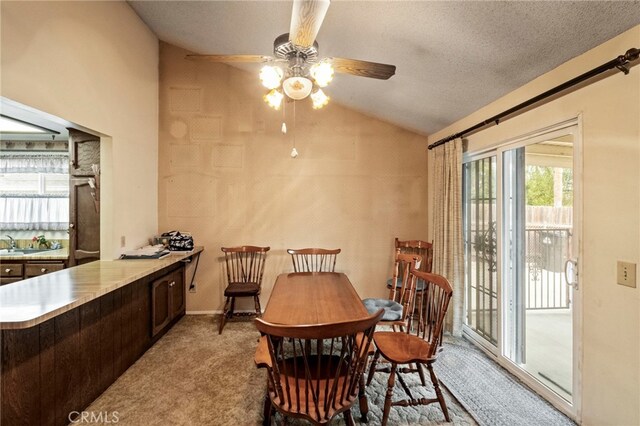 carpeted dining room with lofted ceiling, ceiling fan, sink, and a textured ceiling