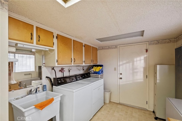 laundry room featuring washer and clothes dryer, sink, a textured ceiling, and cabinets