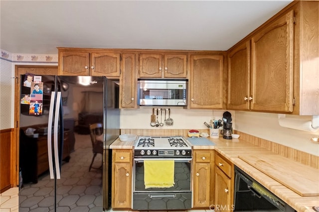 kitchen with light tile patterned floors, black appliances, and wooden counters