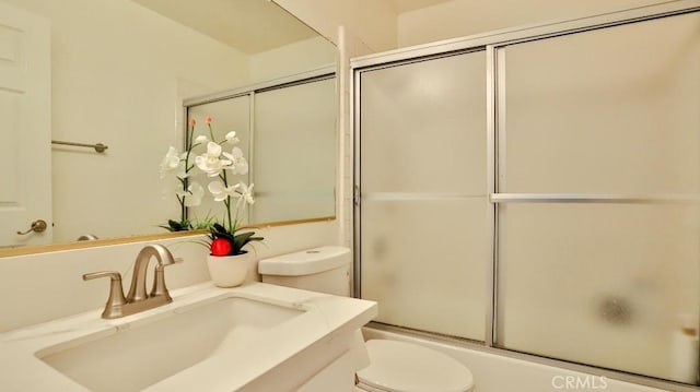 full bathroom featuring toilet, bath / shower combo with glass door, and vanity