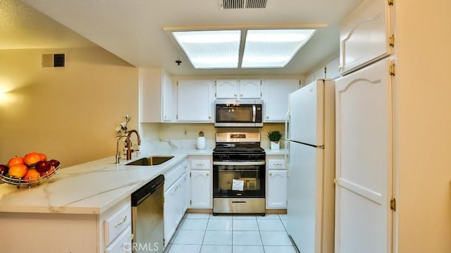 kitchen featuring appliances with stainless steel finishes, white cabinetry, sink, light stone counters, and light tile patterned floors