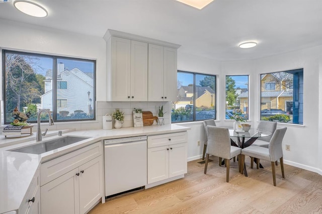 kitchen featuring white cabinets, sink, white dishwasher, and light hardwood / wood-style flooring