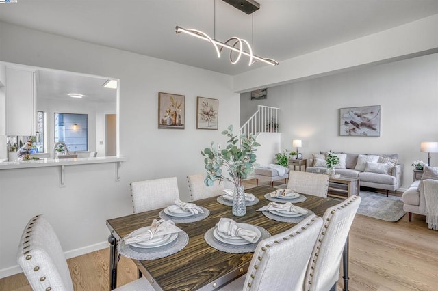 dining space featuring sink, an inviting chandelier, and light hardwood / wood-style floors