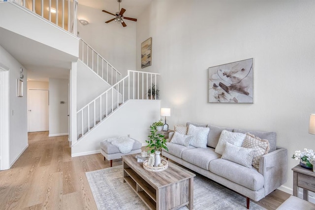 living room with light hardwood / wood-style floors, a high ceiling, and ceiling fan