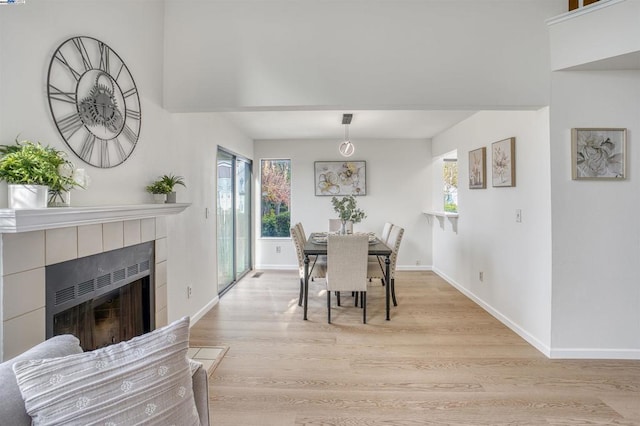 dining area featuring a tiled fireplace and light wood-type flooring