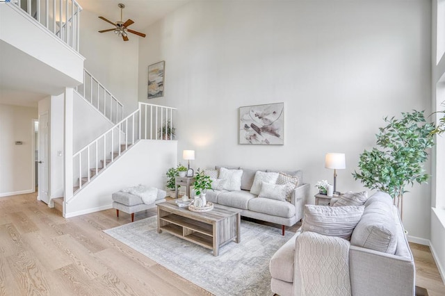 living room with light hardwood / wood-style floors, a towering ceiling, and ceiling fan