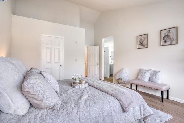 bedroom with ensuite bath, vaulted ceiling, and wood-type flooring