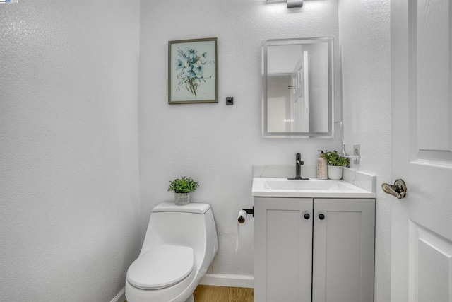 bathroom with hardwood / wood-style flooring, toilet, and vanity