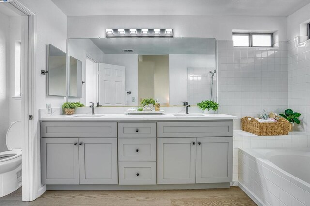 full bathroom featuring toilet, shower with separate bathtub, wood-type flooring, and vanity