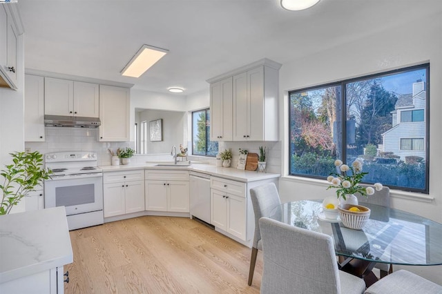 kitchen with white appliances, white cabinetry, decorative backsplash, sink, and light hardwood / wood-style flooring